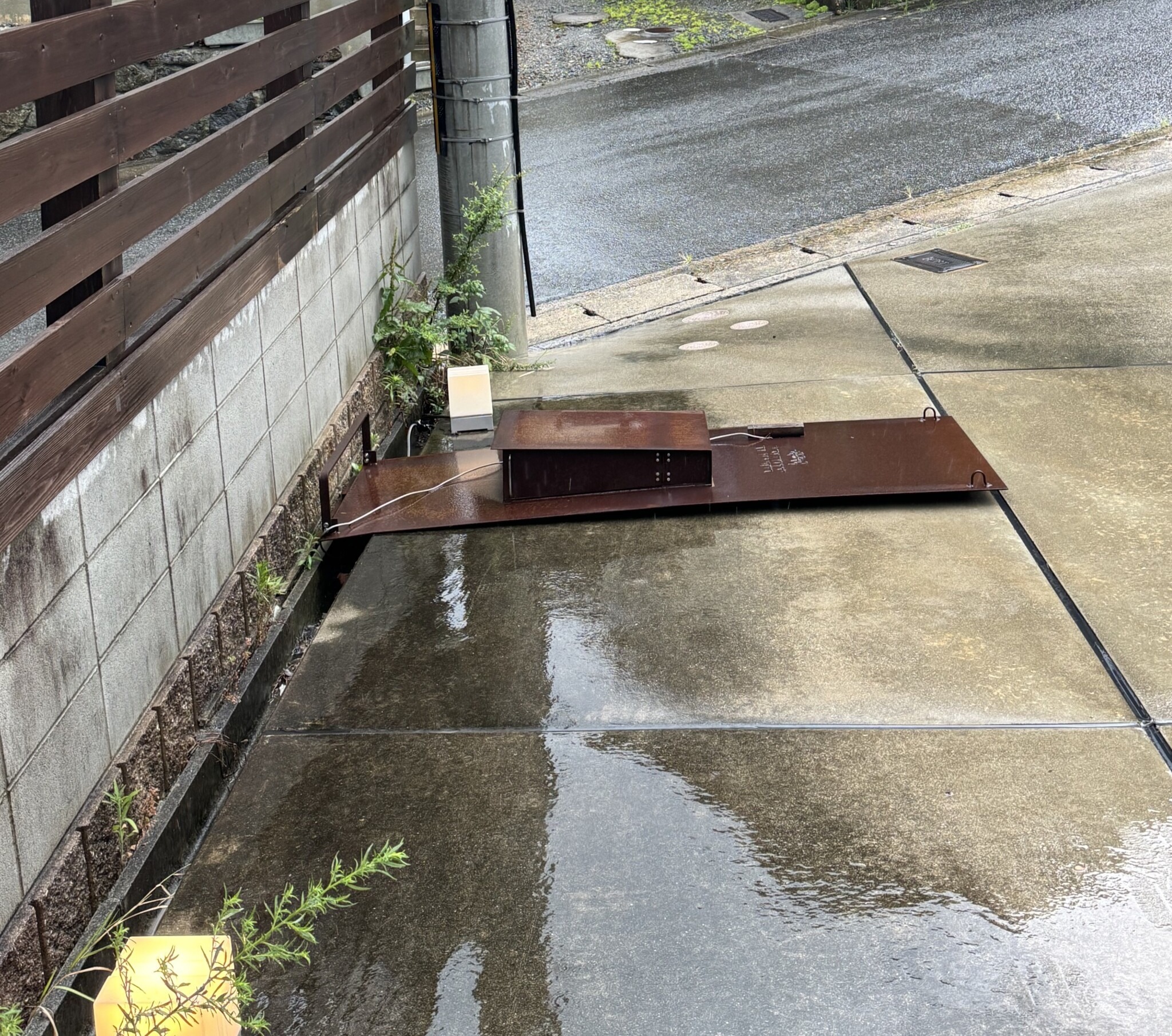 強風で木塀ごと倒れた鉄の門柱とポスト